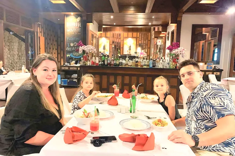A family at a table by the RICE bar with fruit drinks and red napkins