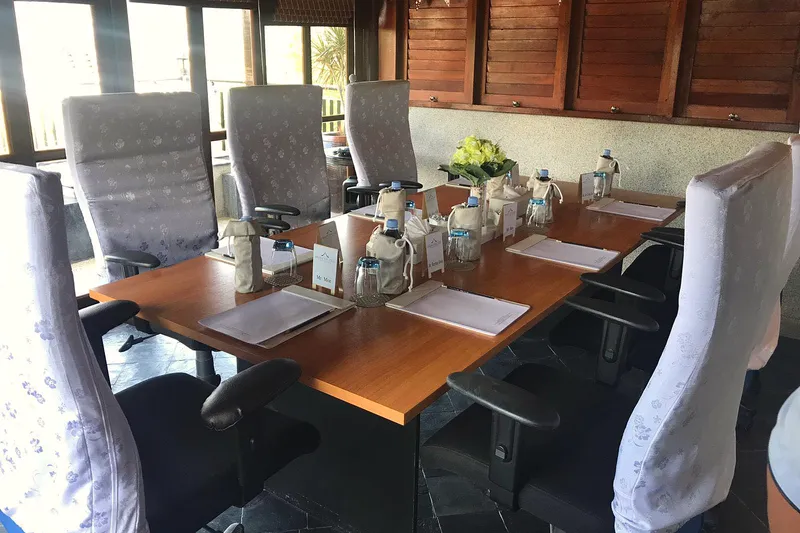 A meeting table laid with notepads, pens and water